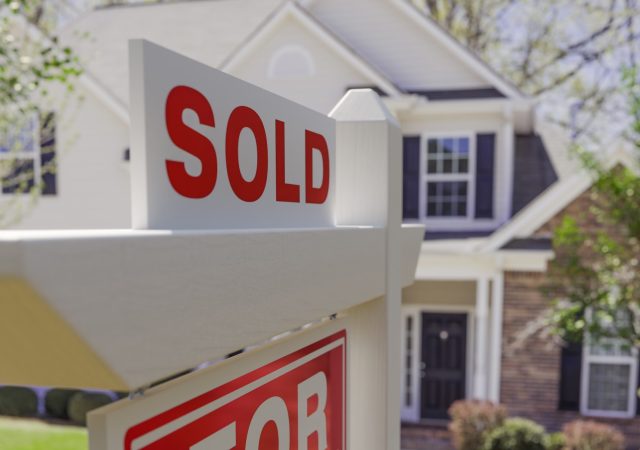 Close-up of Sold Placard On House For Sale Real Estate Sign In Front of New House.